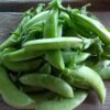 sugar snap climbing peas on a wooden chopping board